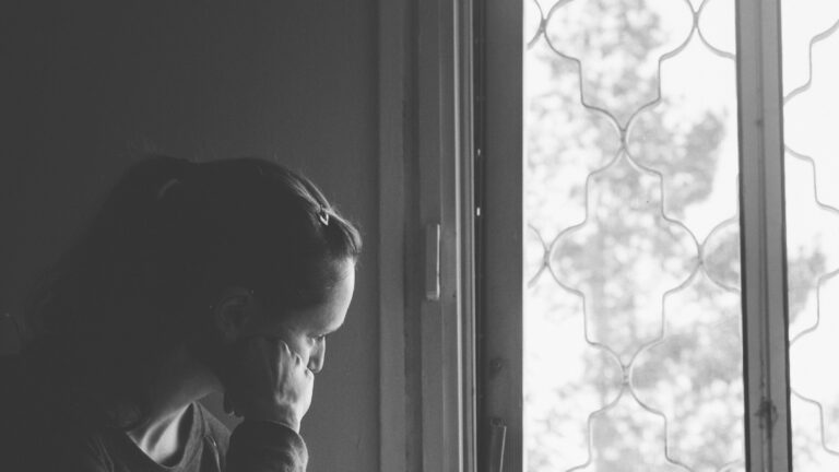 Woman looking out window lost in thought.